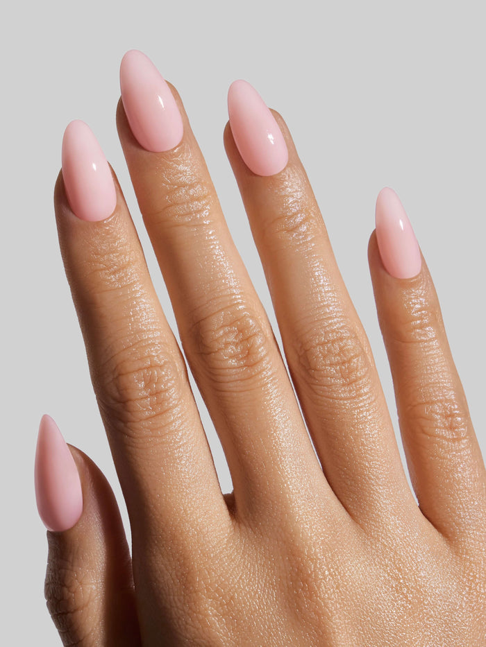 Hand with pink press-on nails on a neutral background