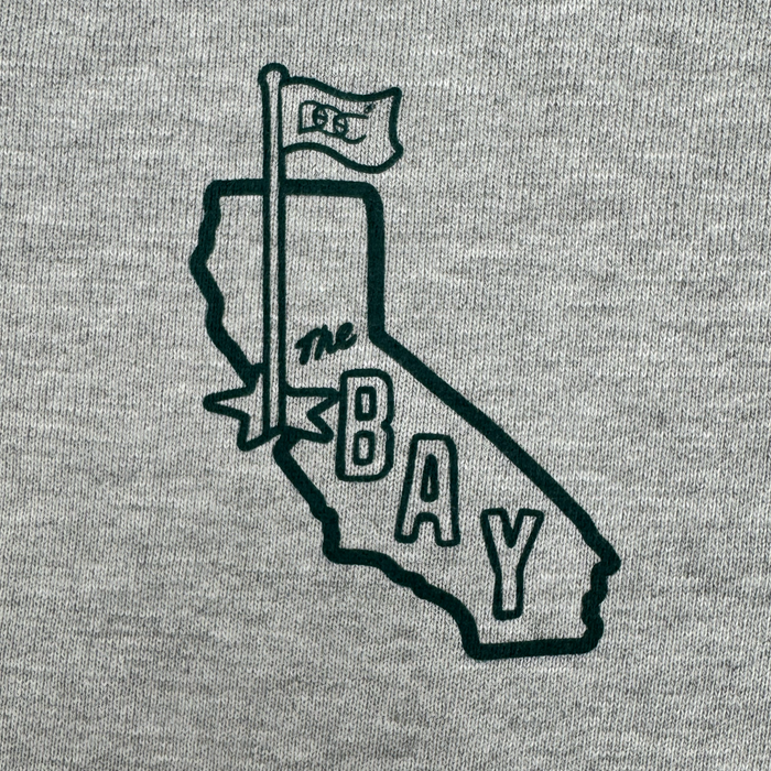 The Bay Area CC Hoodie By DOC from Other features a black outline of California on gray fabric, topped with a flag reading “GSW.” “THE BAY,” referencing the San Francisco Bay Area, is printed inside the state. Crafted from heavyweight fleece, this pullover hoodie is part of The Bay Collection.