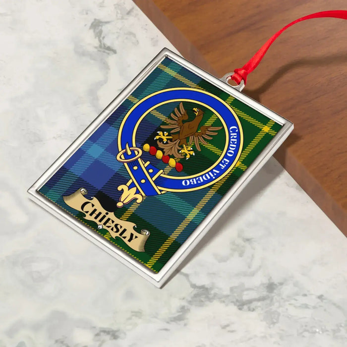 Chiesly ornament hanging from a Christmas tree branch by its satin ribbon