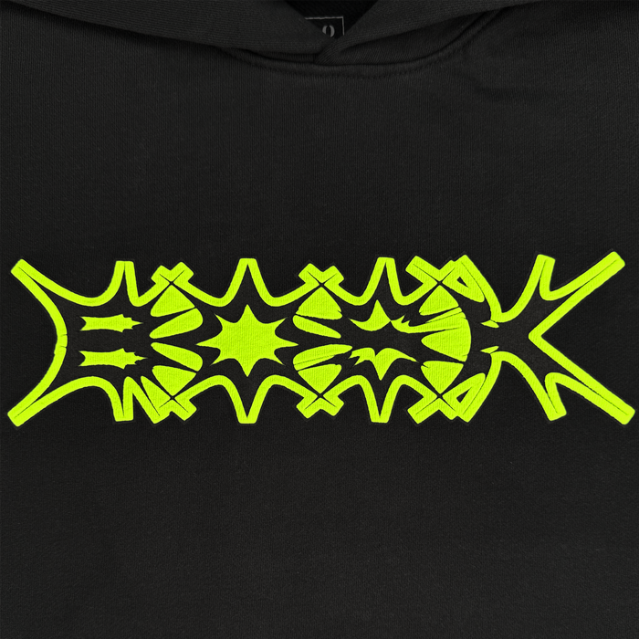 The Distortion Hoodie by Other features a black pigment dye cotton fleece fabric adorned with a neon yellow abstract graphic in the center. Spiky, star-like shapes and symmetrical patterns create a bold, eye-catching visual effect, while the oversized drop shoulder adds a modern edge to this standout piece.