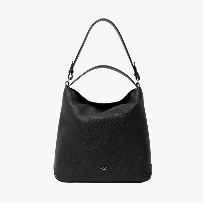 STOW London's Curve in Black leather on a light grey background featuring the detachable shoulder strap and top handle with gold hardware and details