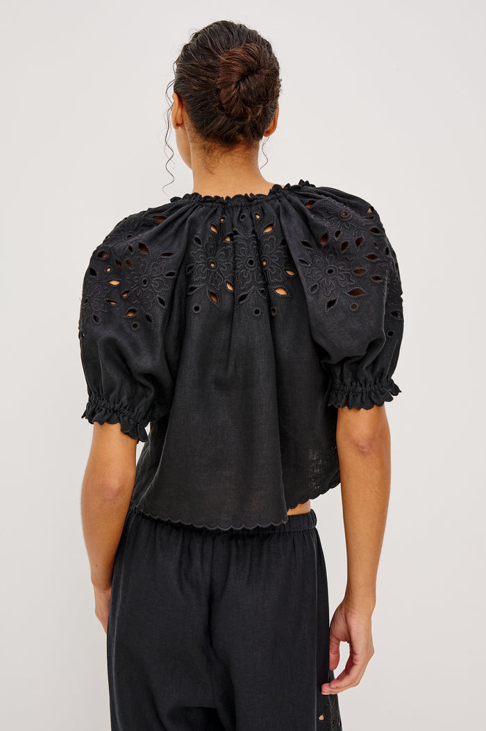 Lizbeth Milkmaid Top in Linen With Floral Eyelet Cutwork Plunging Tie-Front V-Neckline Front Ties Relaxed FIt Short Puff Sleeves in Black Ctolorway - Upper Body Back View Featured on Model