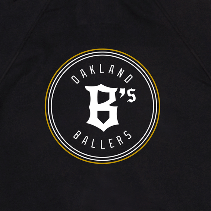 Showcasing a sporty, emblem-style design, the Oakland Ballers Logo Zip by Oakland Ballers features a black backdrop with a white circle highlighted by yellow accents. At its heart, bold white lettering curves around a large, stylized “B’s,” proudly representing the Oakland baseball team in the Pioneer League.