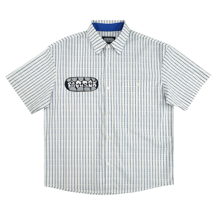 The OG Bottom Shirt by Supported Brands is a 100% cotton short-sleeve button-up with a white base and thin navy stripes, pointed collar, blue inner collar lining, and a bold black and white stylized patch on the left chest.