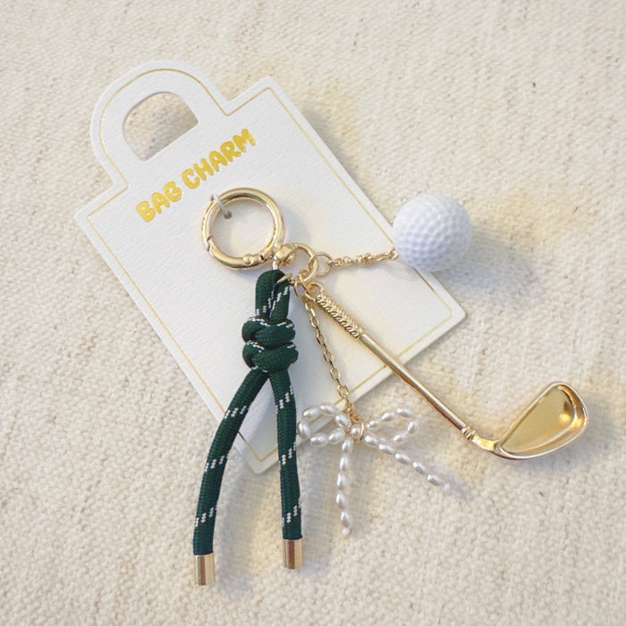 Ellison+Young Par Tee golf bag charm with gold and forest green accents, featuring golf club and ball charms.