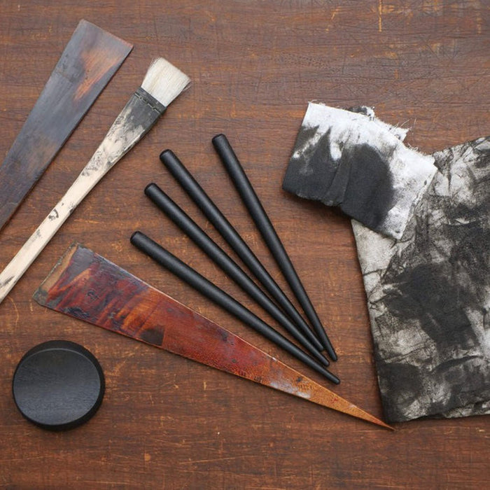Set of brushes and art tools next to black nib holders on wooden table