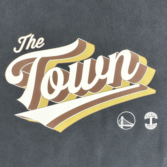 Stylized text reads "The Town" in cream, brown, and gold on a gray background. Below, two white icons—a bridge and a tree with sprawling roots and branches—appear side by side. The Vintage Swash Hoodie by Other celebrates local pride with iconic Oakland-inspired design elements.