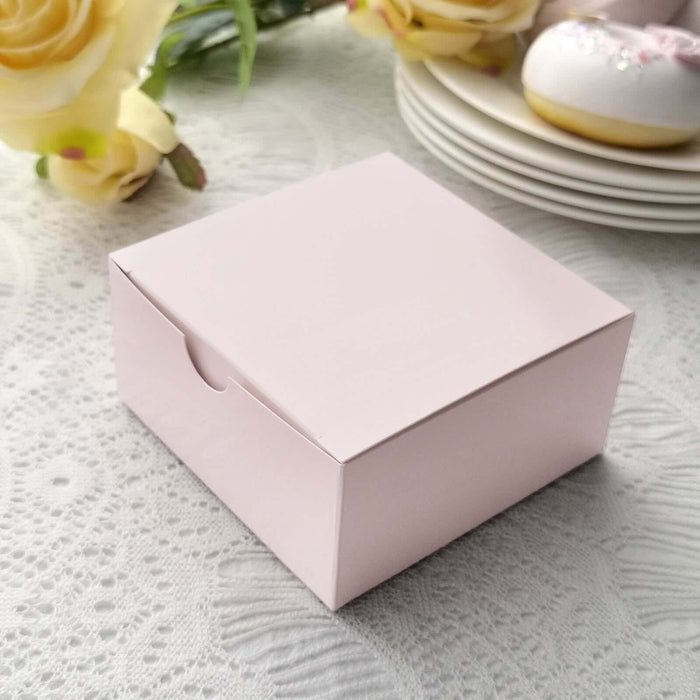 Pink gift box on a lace tablecloth with flowers and plates in the background.