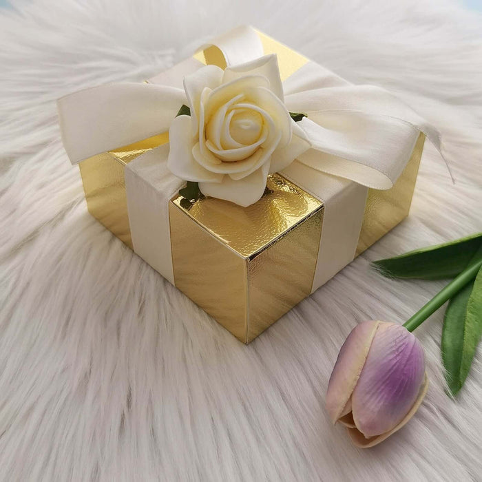 Gold gift box with a white rose and ribbon on a faux fur surface.