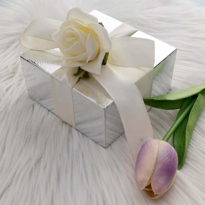 Silver gift box with a white rose and tulip on a soft white fur background.