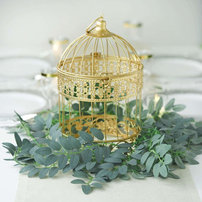 Gold decorative birdcage with greenery on a table setting.