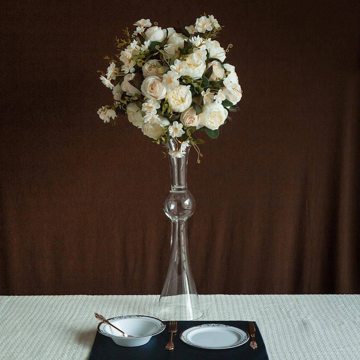 Elegant floral arrangement in a glass vase on a dining table.
