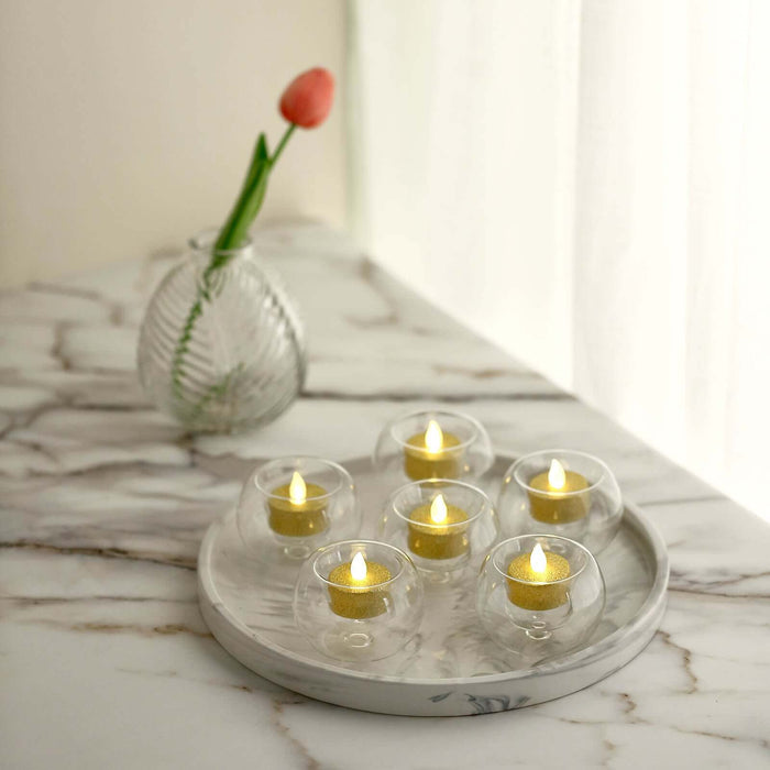 Set of six LED tea light candles in glass holders on a marble tray.