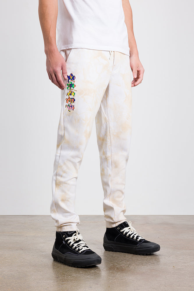 A person wearing 686 Mens Everywhere Double Knit Pant by 686, paired with a white T-shirt and black sneakers, stands on a concrete floor against a plain background.