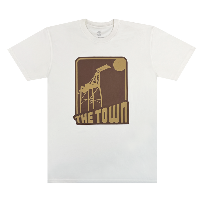 Introducing the 70's Trading Card Tee from Other—a crisp white T-shirt featuring a striking brown and tan graphic of a crane and sun, with “THE TOWN” boldly printed beneath in block letters to match. This design is centered on the chest, making it a standout piece that honors Oakland’s vibrant spirit.