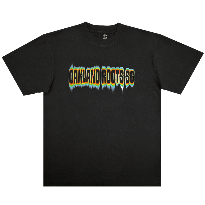 The Acid Tee by Oakland Roots SC is a black t-shirt with “OAKLAND ROOTS SC” in bold, distorted yellow, white, and teal letters outlined in black across the chest. The product is displayed on a plain white background.