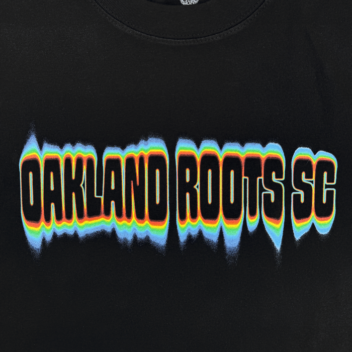The Oakland Roots SC Acid Tee features bold, distorted "OAKLAND ROOTS SC" text with blue, orange, yellow, and white outlines for a vibrant wavy effect on black—perfect for showing your Roots SC pride.