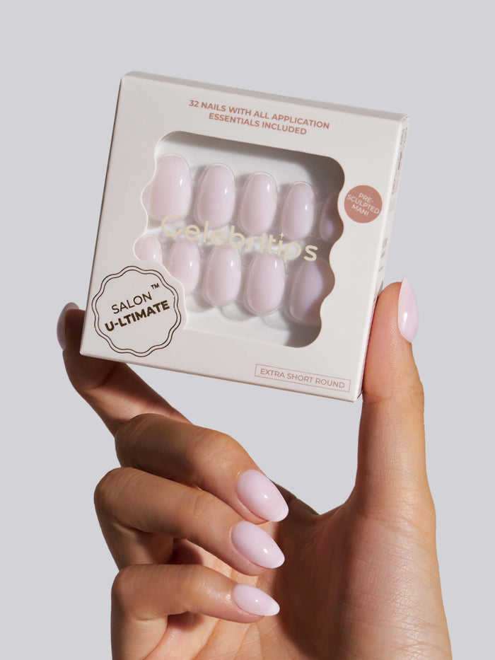 Hand holding a box of press-on nails with a neutral background