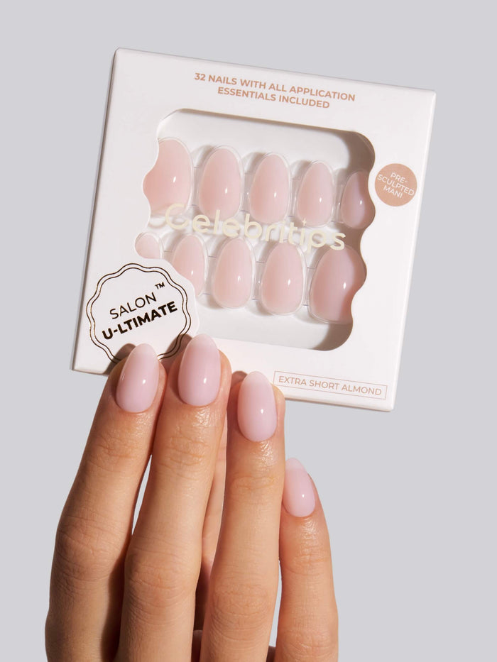 Hand holding a box of 'Salon U-Ltimate' press-on nails with a gray background