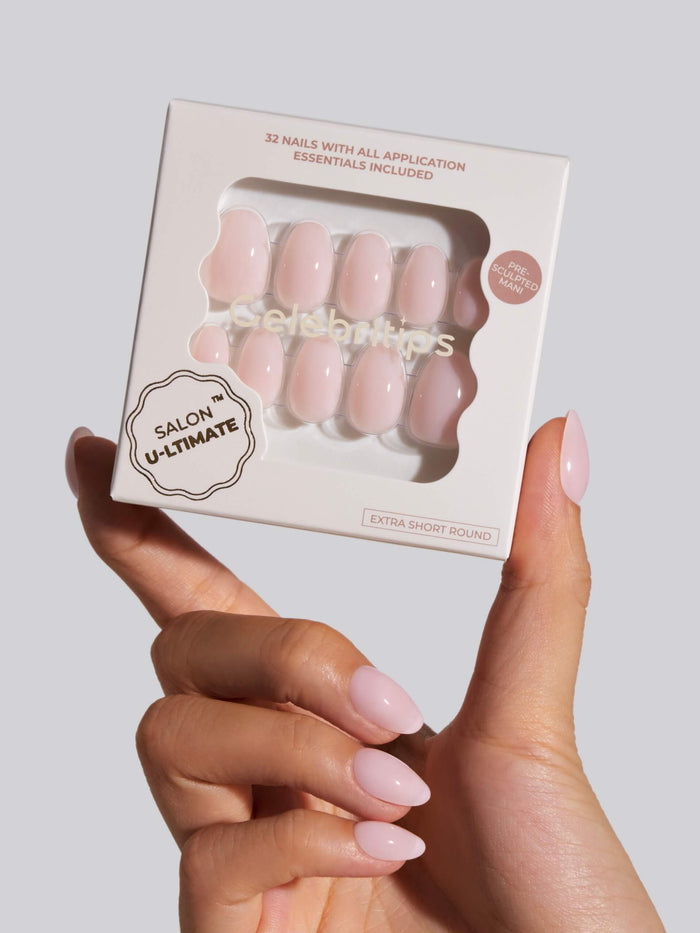 Hand holding a package of press-on nails with a neutral background