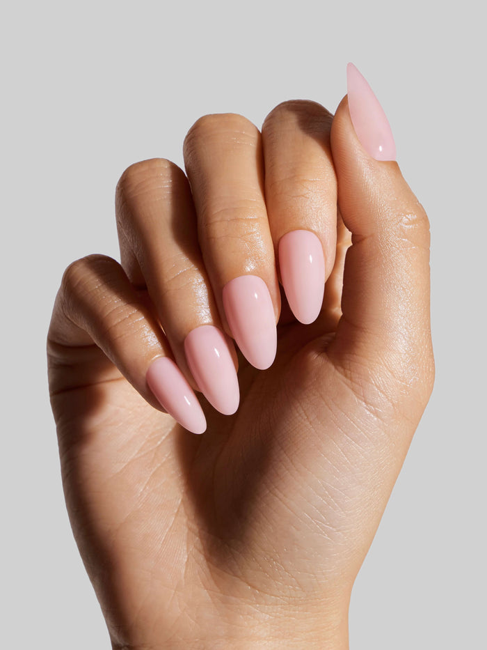 Hand with pink press-on nails on a neutral background