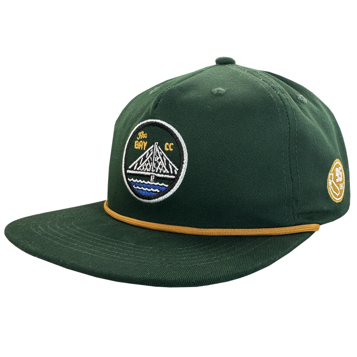 The Bay Area 5 Panel By DOC by Oaklandish features dark green fabric, a flat brim with gold rope detail, and embroidered patches—a “The Bay CC” bridge design up front and a yellow “35” on the side. Part of The Bay Collection.