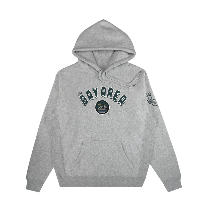 The Bay Area CC Hoodie By DOC by Other is a gray pullover crafted from heavyweight fleece. It features “BAY AREA” in bold, outlined letters across the chest above a small circular graphic, and a line drawing of the Golden Gate Bridge printed on the upper left sleeve. For added comfort and style, this hoodie includes a front pocket and drawstrings.