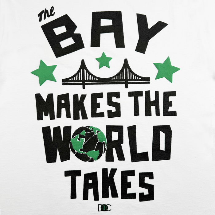 Text on a white background reads “The BAY MAKES THE WORLD TAKES,” blending Bay Area pride with art project flair. Green stars, a silhouette of a bridge, and a green-and-black globe as the “O” in “WORLD” add visual interest to this heavyweight cotton t-shirt design. A small green logo sits at the bottom. This is the Bay Bridge Tee by DOC from Other.