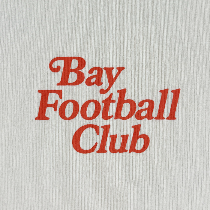 The Bay FC Jubilee Tee features bold red “Bay Football Club” text, centered on heavy-weight white cotton. This classic fit from Bay FC offers a timeless, simple design perfect for any fan.