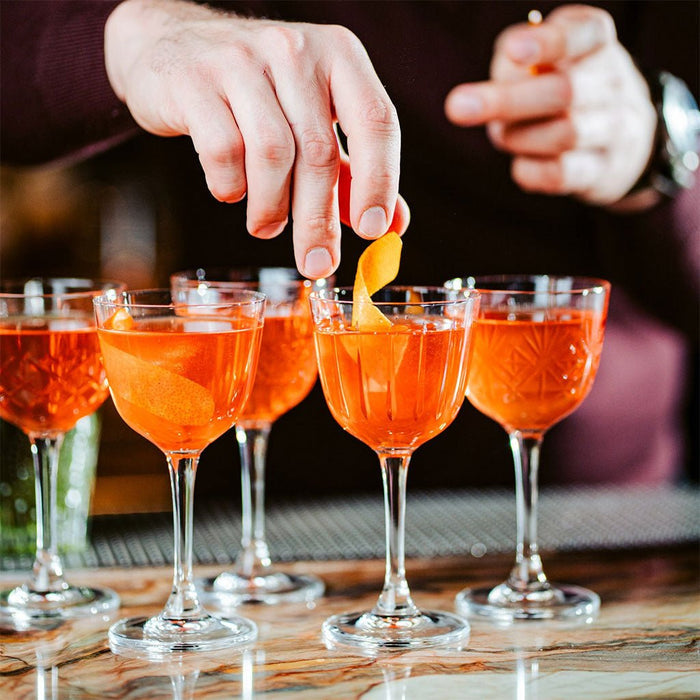 Cocktails being garnished with orange slices on a bar counter.