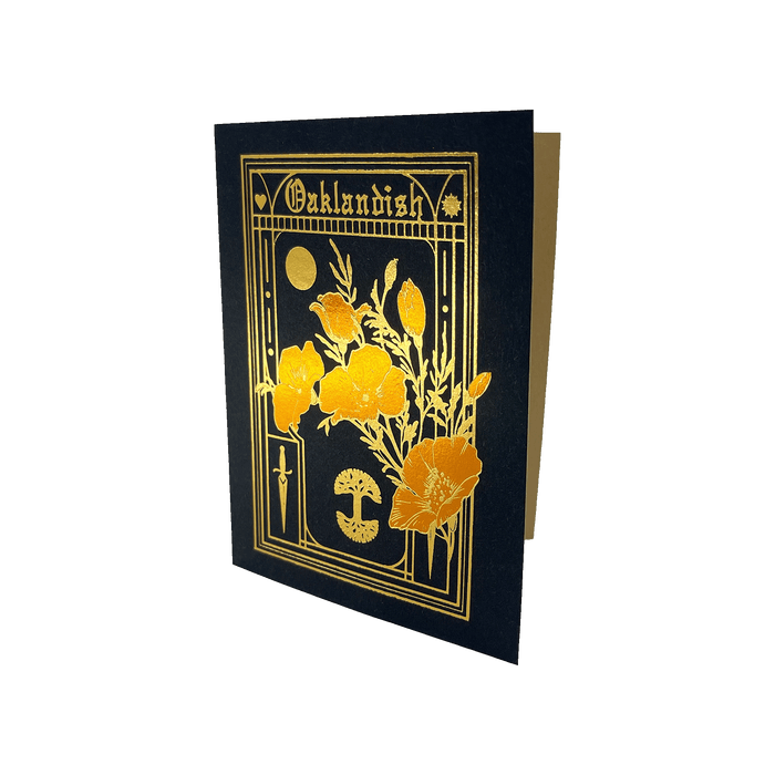 A Never Elsewhere Blossom Card with a black cover adorned with gold foil details. The front features an intricate design of poppies, a cross, a mushroom, and a crescent moon on recycled kraft paper, framed by geometric patterns. The top of the card displays "Oaklandish" in an ornate, stylized font.