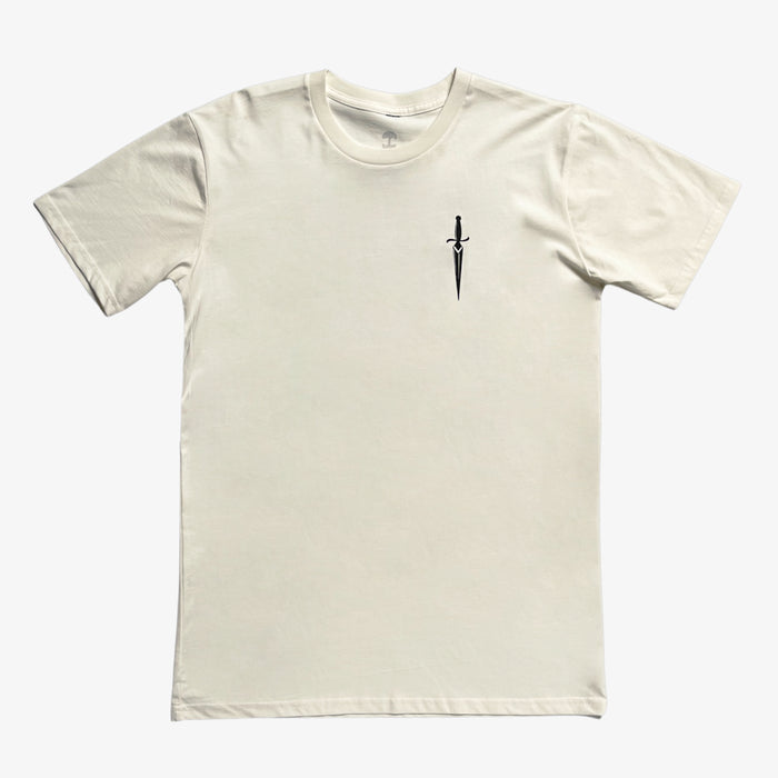 The Blossom Tee by Oaklandish is a plain, short-sleeved, cream-colored classic fit T-shirt featuring a simple design of a small black sword pointing downward on the left chest area. The sword adds a subtle accent to the otherwise clean and minimalist 100% cotton shirt.