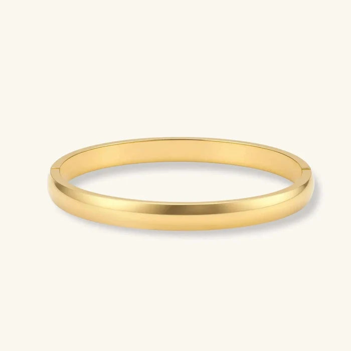 Bold Hinge Bangle bracelet in polished gold-tone metal, with a smooth solid band, oval shape and discreet hinge joints