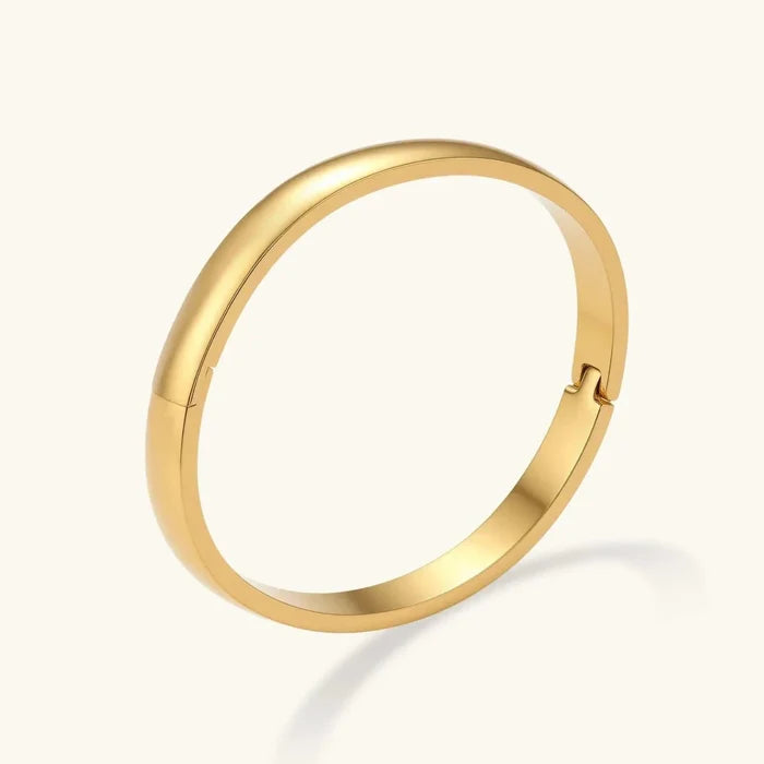 Bold Hinge Bangle in polished gold-tone metal with a smooth, solid oval band and discreet side hinge.