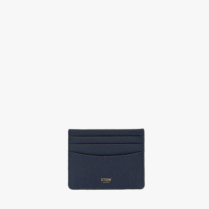 STOW London's Cardholder in Navy pebbled leather on a light grey background featuring a fine gold embossed logo on the front bottom.