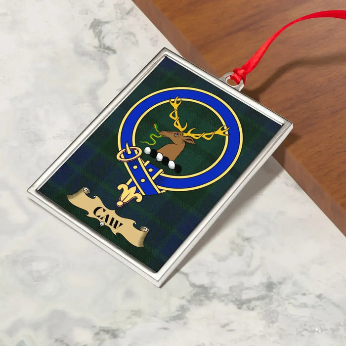 Caw ornament hanging from a Christmas tree branch by its satin ribbon