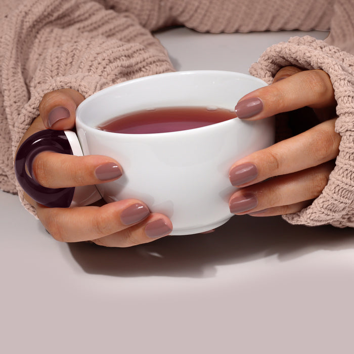 Hands with LONDONTOWN mauve polish hold a white mug of Chai. The wearer is in a knitted sweater against a soft taupe background.