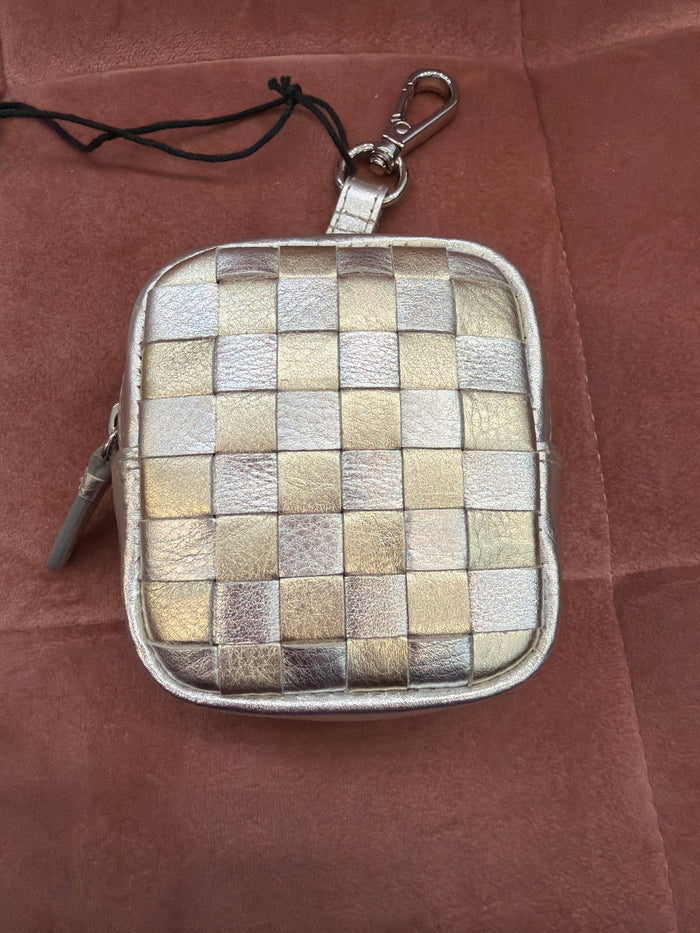 ili New York checkerboard pouch charm hanging from a bag, featuring a black and white checkerboard pattern and gold accents.
