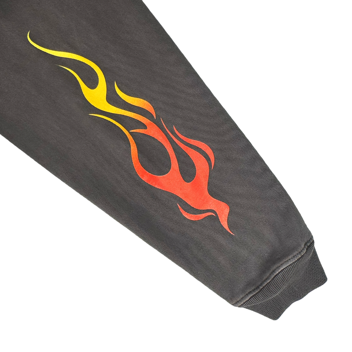 The Chopper Heavy Hoodie by Other features an oversized black drop shoulder design with a striking flame graphic that fades from yellow to red along the sleeve. A ribbed cuff adds a classic touch, making this pullover hoodie a bold style statement. The product is displayed against a white background.