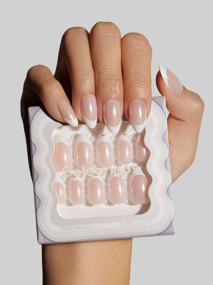 Hand holding a set of press-on nails with a neutral background
