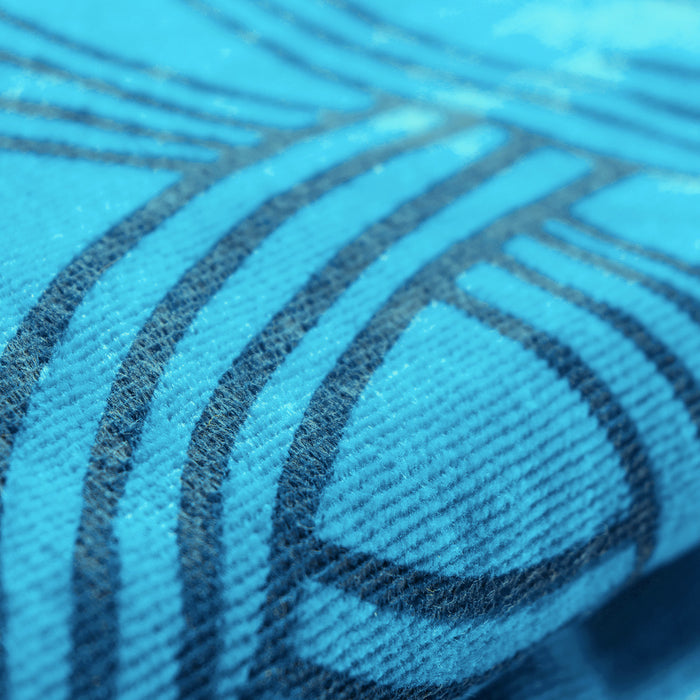 Close-up view of the Oaklandish Classic Logo Beach Towel, an oversized plush beach towel made from cotton terry velour, featuring a detailed pattern of dark blue lines and curves. The fabric's texture is visible, with small fibers and a slightly ribbed surface, creating an abstract, geometric design accentuated by the contrasting colors.