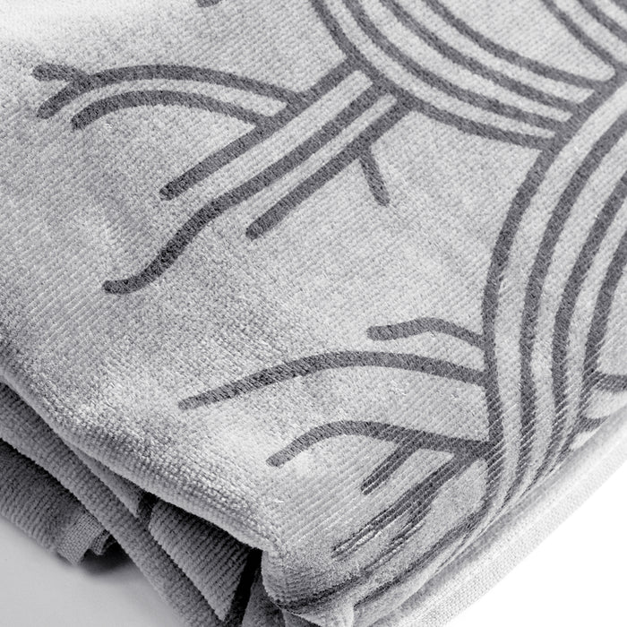 A close-up of the oversized Classic Logo Beach Towel by Oaklandish, folded to reveal its abstract, elegant darker gray tree design. Made from 100% ringspun cotton, the fabric appears super soft and plush with visible textures and fibers. The towel's folds highlight the intricate pattern and high-quality material.