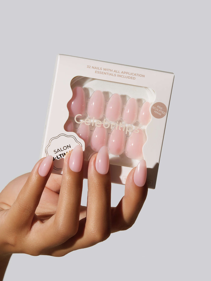 Hand with pink nails holding a box of Celebritips press-on nails.