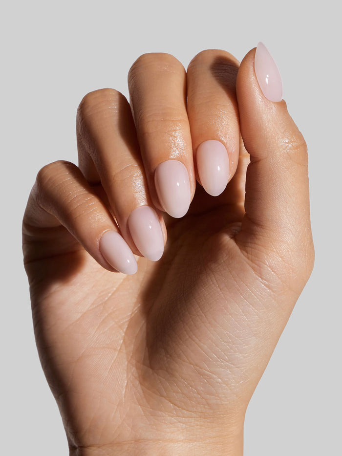 Close-up of a hand with Coconut Milk press-on nails on a neutral background
