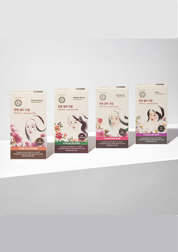 Four boxes of a cosmetic product with floral and portrait designs on a white background