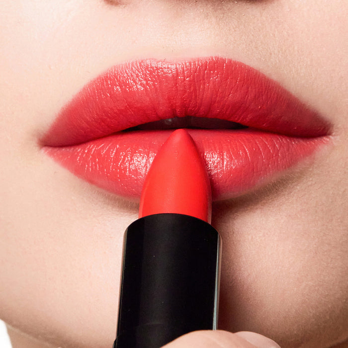 Close-up of a person applying color beautiful lipstick to their lips.