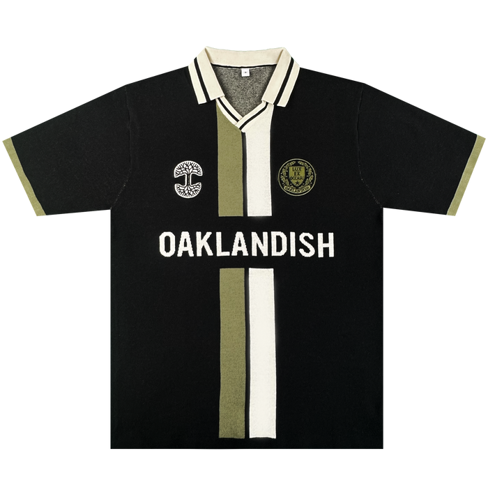 The Oaklandish Ease Jersey is a black unisex short-sleeve knit collar shirt with olive and white center stripes, bold “OAKLANDISH” across the chest, tree logo left, circular patch right, and olive trim.