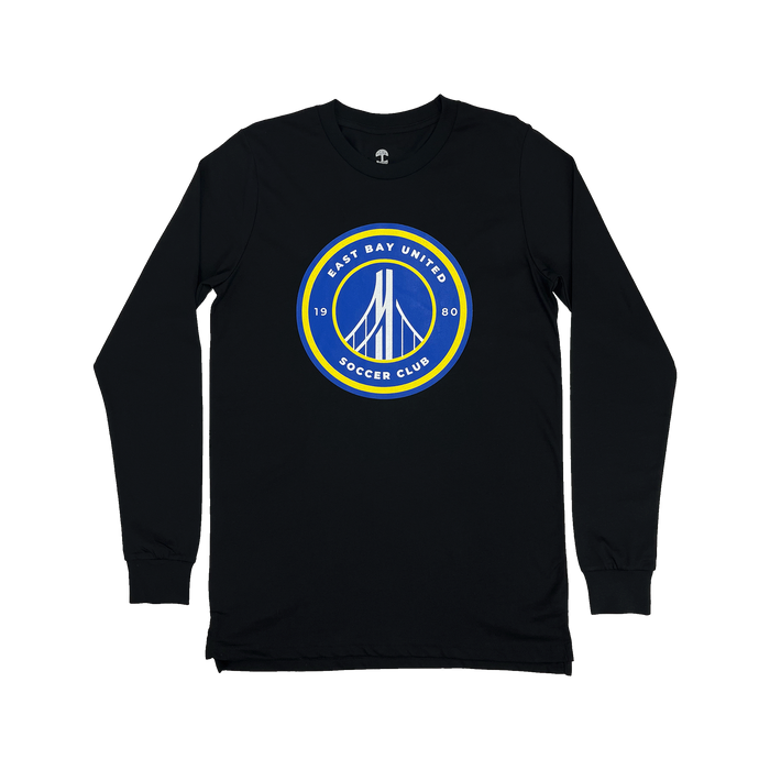 The EBU Long Sleeve Tee by Supported Brands is a black shirt with long sleeves, featuring a circular emblem prominently displayed on the front center. The emblem showcases a blue background with a white bridge illustration at its core, encircled by a yellow border. Surrounding the bridge design, the text "East Bay United Soccer Club" and "1980" are finely written in white letters, celebrating the storied youth soccer club.