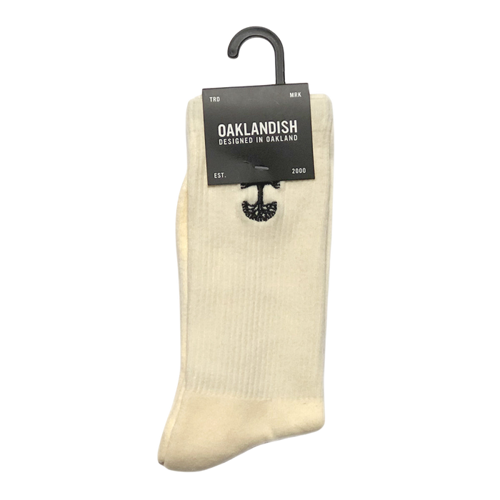 A pair of yellow cotton Embroidered Logo Socks is displayed against a plain background. Neatly folded and held together by a black hanger, they feature an embroidered logo. Attached to the hanger is a dark gray label reading "Oaklandish, Designed in Oakland," accompanied by an image of an oak tree. The label also notes "TRD MRK" and "EST. 2000".