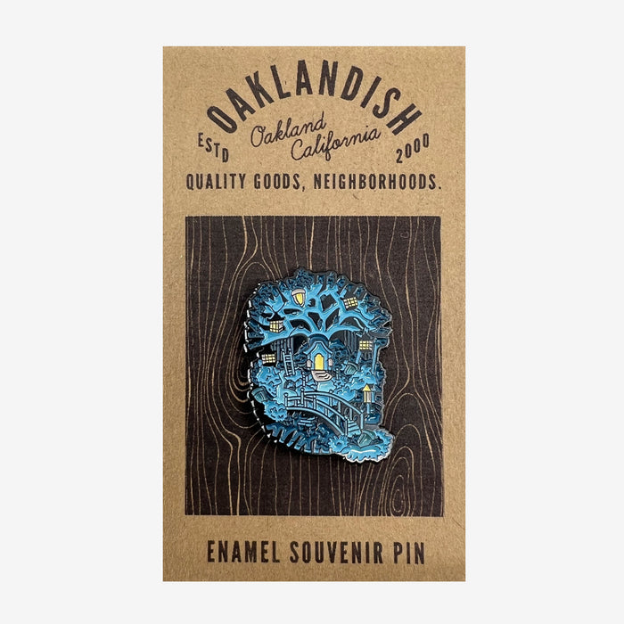 The Enamel Pin - Treehouse from Oaklandish showcases a vibrant nightscape of Oakland, California, with city landmarks in blue and yellow hues. It is mounted on a brown card that features the text "OAKLANDISH," "Est'd Oakland, California 2000," and "Quality Goods, Neighborhoods," with "Enamel Souvenir Pin" at the bottom. This pin is perfect for fans of stylish accessories.